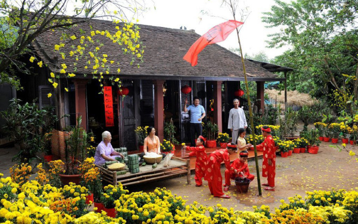 Gia đình sum vầy bên mâm cỗ Tết truyền thống với bánh chưng, bánh tét và hoa mai, biểu tượng của sự ấm cúng, đoàn viên trong văn hóa Việt Nam