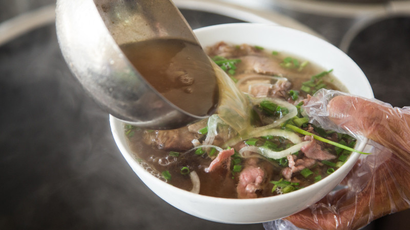 Một bát phở bò Hà Nội nóng hổi với thịt bò thái lát, hành lá, rau thơm và nước dùng trong